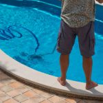 man vacuuming the bottom of his swimming pool